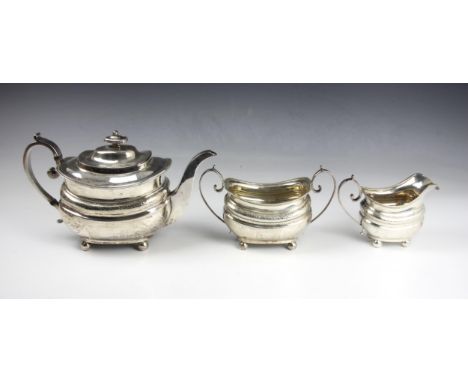 A George III silver three piece tea service, Naphtali Hart, London 1812, comprising teapot, sugar bowl and milk jug, the scro