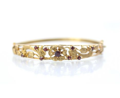 A 9ct yellow gold Victorian style bangle, the openwork bangle with flowerhead and foliage detail, set with nine graduated rou