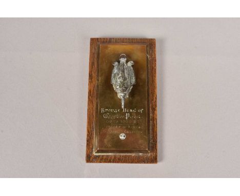 A Bronze Head of Egyptian Priest, circa 1600BC - Valley of the Kings, Carnarvon Collection, on brass plaque and wooden wall m