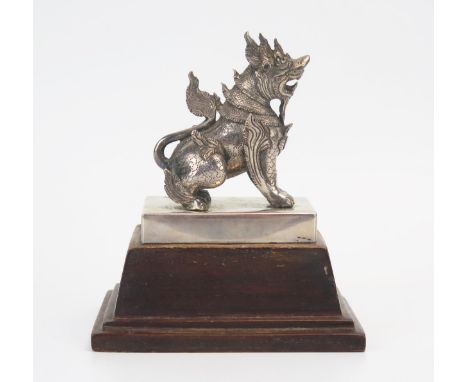 A Burmese silver model of a Chinthe (Temple Lion) of traditional design, mounted on a rectangular polished wood base, overall