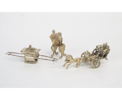 A continental silver model of a carriage (lacks one wheel), a Chinese silver model of a sedan chair and a silver model of a c