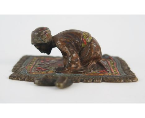 An Austrian cold painted model of an Arab praying on a prayer rug, unsigned, 6.5cm long. 
