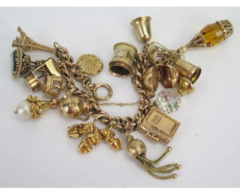 A 9ct Gold Charm Bracelet set with sixteen charms including the Eiffel Tower, the Three Wise Monkeys, a wishing well, articul