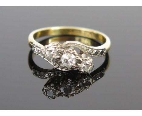 A Diamond Three Stone Crossover Ring in an 18ct gold and platinum setting, central stone c. 3mm, size K, 2.5g 