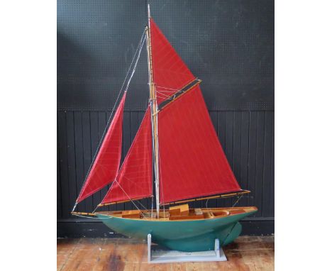 A painted fibreglass and wooden model of a single masted sailing ship, with green painted hull, simulated planked decking, po
