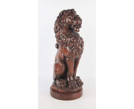 A carved oak model of a lion sejant, on a circular base, 44cm high. 