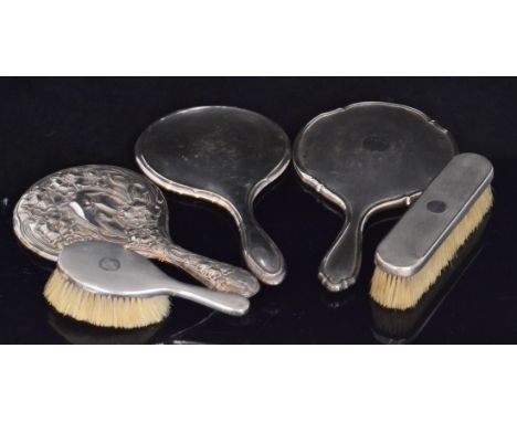 A small collection of hallmarked silver mounted dressing table items to include a circular floral embossed hand mirror, two f