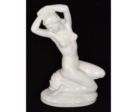 A Karl Ens Volkstedt blanc de chine figure modelled by P.W Goebel as a seated nude with her arms above her hand and sat upon 