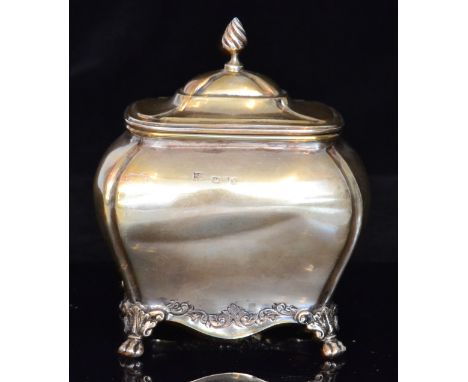 An Edwardian hallmarked silver tea caddy of bombe form with hinged lid and wrythen finial, chased scroll border decoration to
