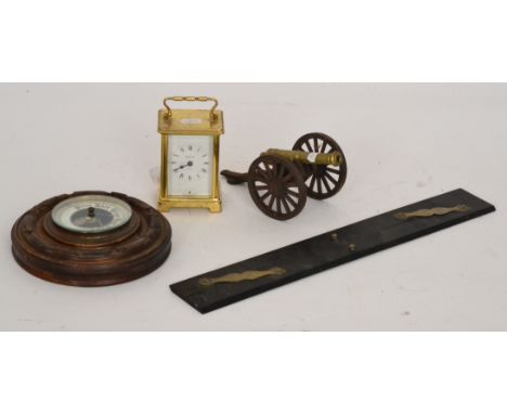 A miniature scale model of a brass canon, a 20th Century carriage clock, an ebony parallel rule and a small aneroid barometer