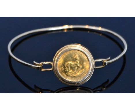 A 1/10 Krugerrand coin dated 1982, loose mounted to a 9ct stiff bangle, total weight 8g.