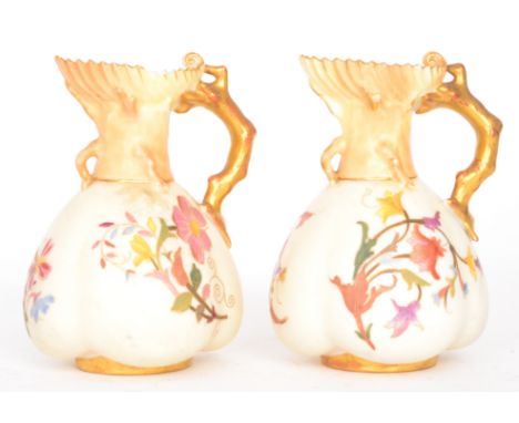 A pair of late 19th Century Royal Worcester jugs, each decorated with floral sprays against an ivory ground, the handles form
