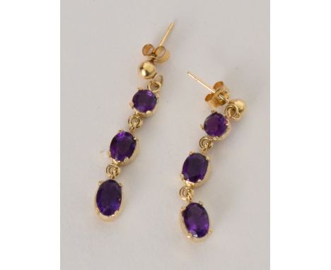 A pair of 9ct gold and amethyst pendant earrings, each with three graduated mixed cut amethysts, claw set to butterfly fittin