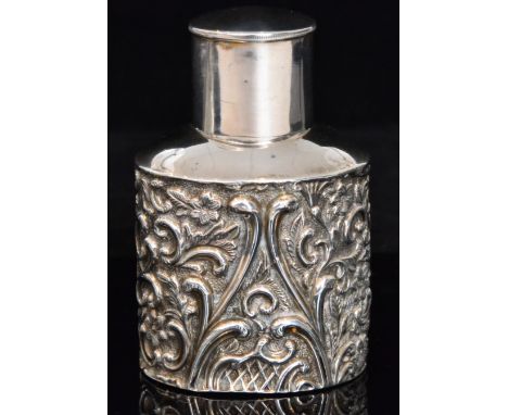 A George V hallmarked silver tea caddy of compressed ovoid form with embossed foliate and C scroll decoration, plain pull off
