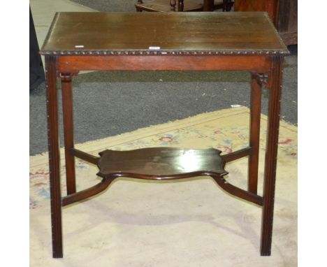 An early 20th Century mahogany side table with a stylised stretcher shelf, with fret-cut spandrels above the carved reeded le