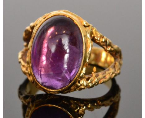 A later 20th Century 18ct hallmarked amethyst single stone ring, collar set cabochon stone to bark effect spilt shoulders, Lo