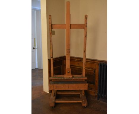 A beech adjustable studio easel with H frame on sled supports resting on casters. H.185cm. 