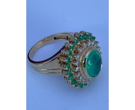 A large 18ct yellow gold dress ring set with a large 3.3ct Colombian emerald and surrounded with a 2 rings of emeralds and di