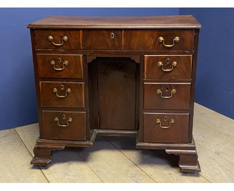 George III figured mahogany kneehole writing desk of 7 drawers with brass drop handles flanking a recessed cupboard (locked) 