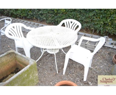 A circular metal ornate garden table and three plastic, garden chairs