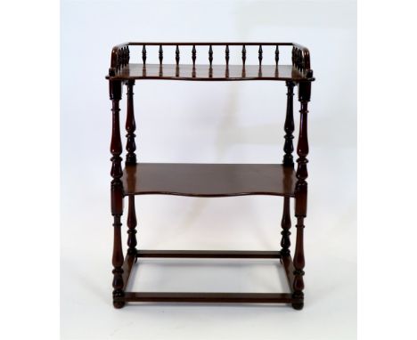 A Victorian mahogany two tier what-not with spindle gallery shelf above two serpentine front tiers spaced by baluster pilaste