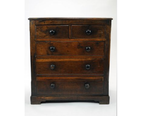 A early 19 th century country oak chest of three long and two short drawers, the chamfered sides enclosing stained handles on