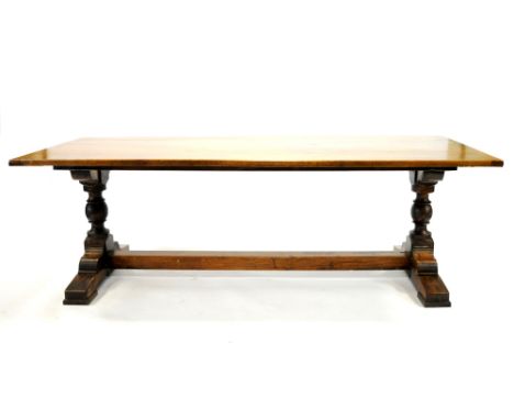 A stained oak refectory table, the planked top above twin turned supports on a large bracket base united with a single beam s