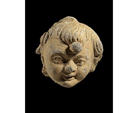 Kleiner Kopf eines Kindes. Gandhara, 4. - 5. Jh. n. Chr. H (ohne Ständer) 8cm. Sandstein. Leicht gewendetes, lächelndes Gesic