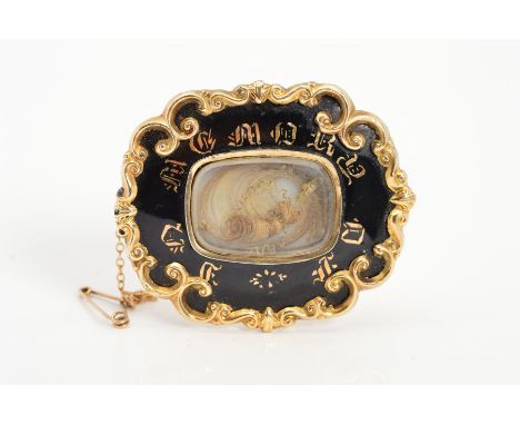 A MID VICTORIAN MEMORIAL BROOCH, the central glass panel encasing an arranged lock of hair with split pearl gathering, to the