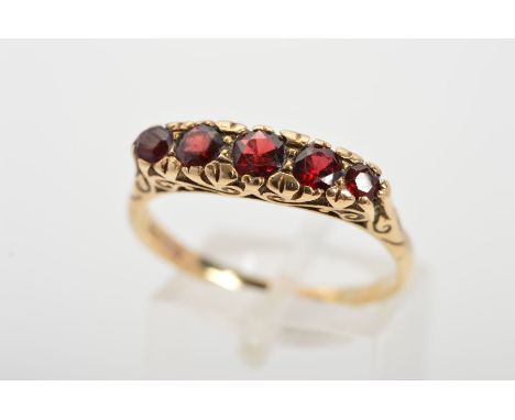 A 9CT GOLD GARNET RING, designed as a graduated row of five circular garnets to the scrolling gallery, with 9ct hallmark for 