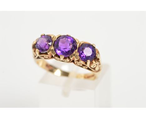 A 9CT GOLD AMETHYST THREE STONE RING, designed as  three graduated circular amethysts to the scrolling gallery, with 9ct hall