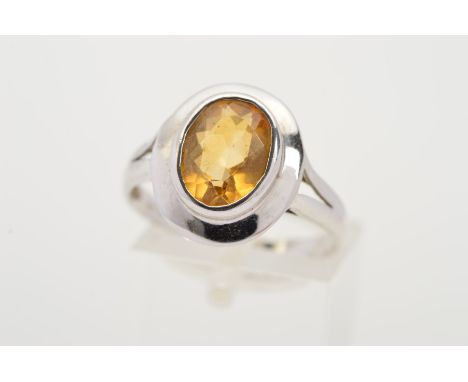 A 9CT WHITE GOLD CITRINE RING, the oval citrine within a collet setting to the plain surround to the bifurcated shoulders, wi