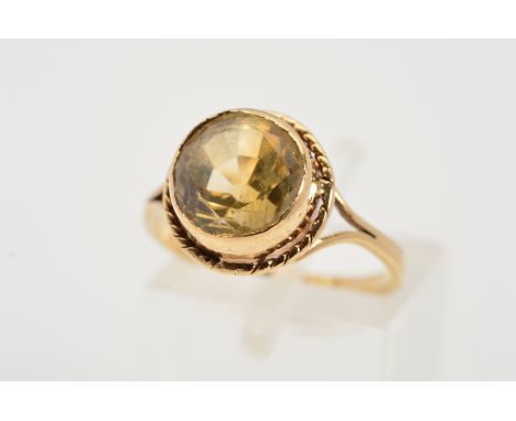 A CITRINE RING, the circular citrine within a collet setting to the rope twist surround and bifurcated shoulders, stamped 9ct