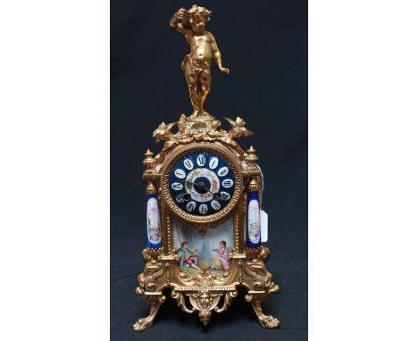 A French mantel clock with eight-day movement in ornate gilt spelter case with inset porcelain panels and dial, and putti fin