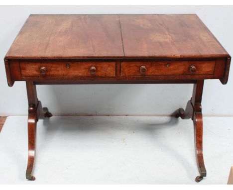 A Regency mahogany sofa table, the top with a pair of drop flaps, over two short drawers and supported on twin end pillars wi