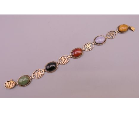 A 14 K gold jade bracelet set with various cabochon stones and Chinese symbols. 18 cm long. 12.7 grammes total weight.