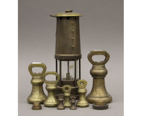 A quantity of brass weights and a miner's lamp.