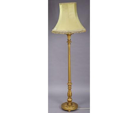 A giltwood standard lamp having a fluted &amp; turned centre column, &amp; on a circular base with bun feet, with shade, 194c