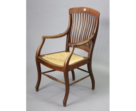 An early 20th century beech comb-back elbow chair with woven-cane seat, &amp; on shaped legs with a turned front stretcher.