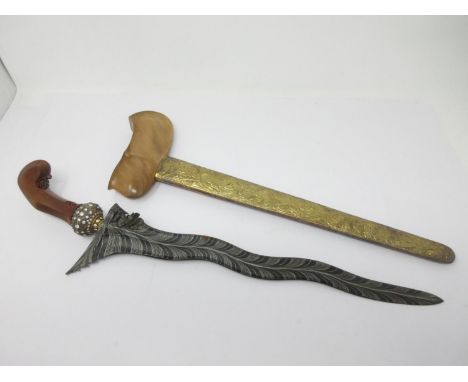 An Indonesian Ceremonial Dagger with dragon decorated blade, carved wooden grip and paste set pommel, the gilt metal scabbard