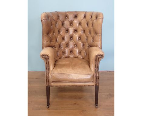 A Georgian style button upholstered Library Chair with barrel-back, shaped arms, on squared tapering front supports and caste