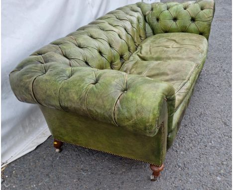 A green leather button upholstered Chesterfield Settee on turned walnut front supports and casters, (reupholstered by Joseph 