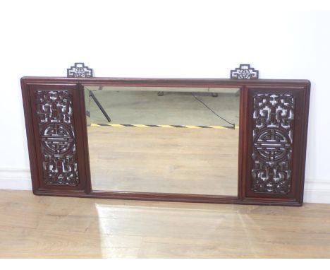 A Chinese rosewood framed Mirror with pierced design incorporating bats to the corners flanking a bevelled rectangular plate 