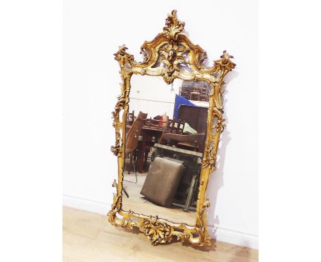 A 19th Century gilt Wall Mirror in the rococo manner with asymmetrical leafage scroll surmount and scrolls and foliage to the