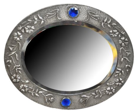 An Arts and Crafts beaten pewter framed oval mirror with bevelled edge and central blue stone decoration, width 63cm.