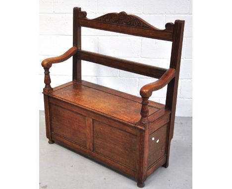 An early 20th century oak monks bench with carved decoration to the top, width 97cm.