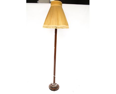 A mid-century wooden standard lamp. Mounted on a stepped circular base, with a yellow shade, H150cm (excluding fittings)