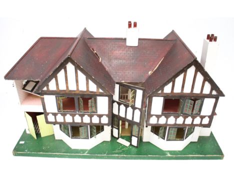 A vintage Tri-ang 'Stockbroker' mock-Tudor dolls house. Containing five rooms, a hallway and a garage, mounted on a green bas