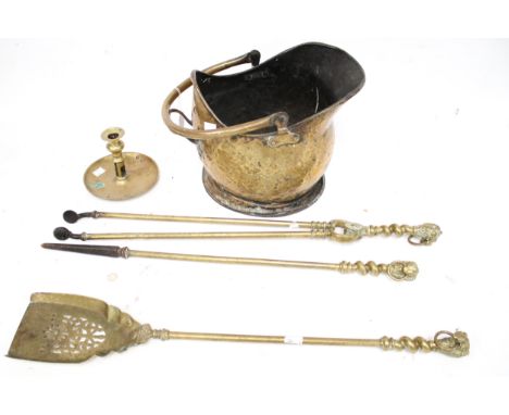A set of three brass fire irons, a coal scuttle and a candlestick. The fire irons with lions head handles, L68cm, the coal sc