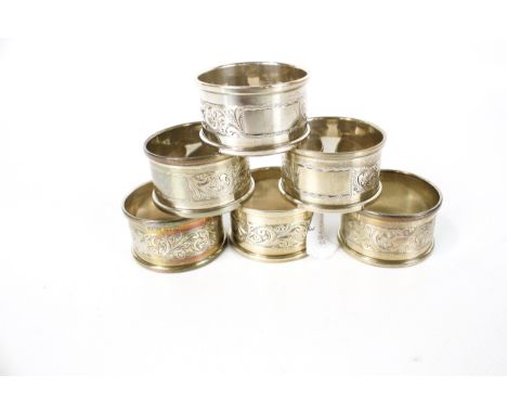A matched set of six vintage silver napkin rings. Each with raised borders and a central band engraved with foliate scrolls a